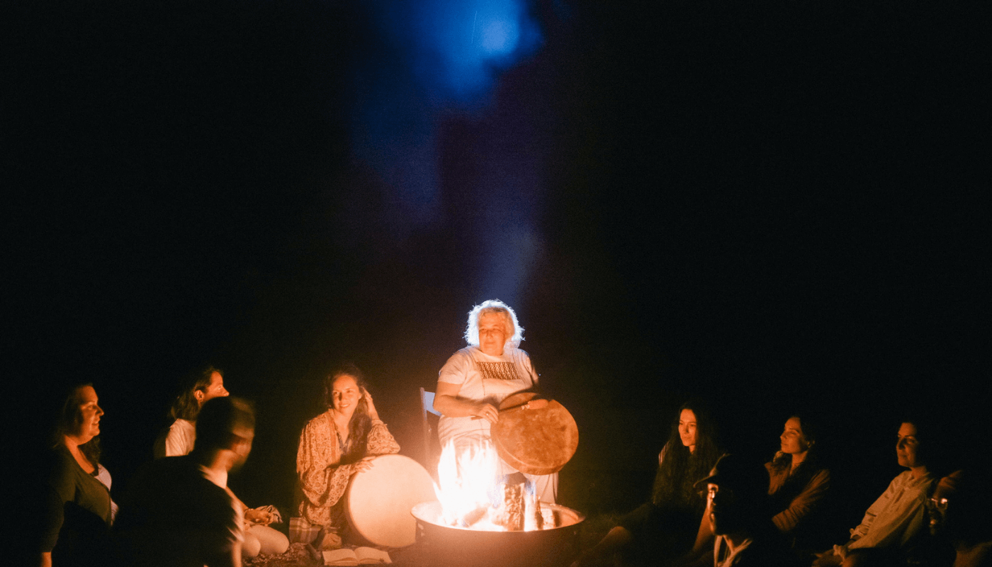 Sarah playing a drum around the fire